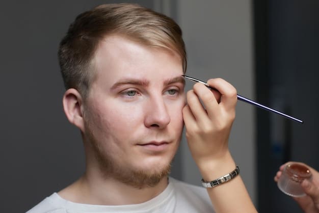 A close-up of a man's face as he uses a spoolie brush to groom his eyebrows, demonstrating the technique for achieving a clean and defined look.