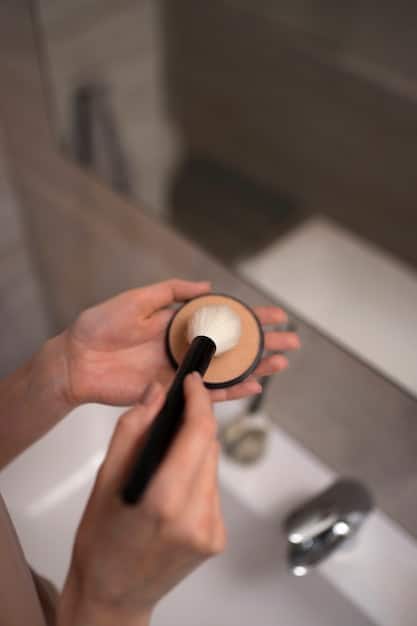 Close-up of a man's hands applying a matte, long-wearing foundation to his face using a makeup sponge. Focus on the product's texture and application technique.