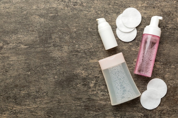 Close-up of different types of makeup removers (micellar water, cleansing wipes, oil-based remover) arranged neatly on a shelf with skincare products, showcasing the variety of options available.