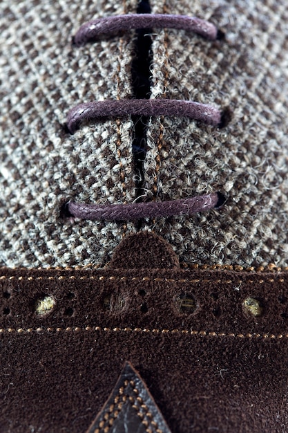 A close-up shot of high-quality unisex leather boots with intricate stitching and a durable sole. The leather is slightly distressed, giving it a vintage look. The boots are set against a rustic wooden background, accentuating their craftsmanship and ruggedness.