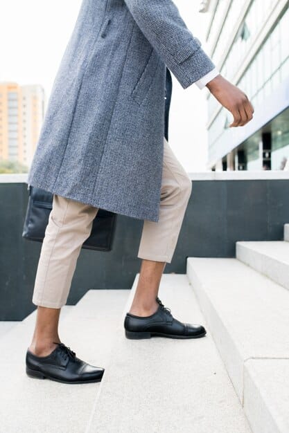 A person wearing minimalist black slip-on sneakers with a pair of tailored trousers and a simple white shirt, showcasing how slip-ons can be incorporated into a semi-formal outfit.