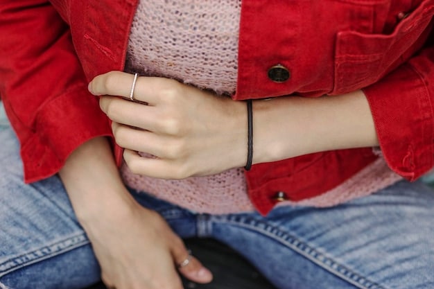 Close-up shot of hands wearing various minimalist unisex rings, including simple bands, geometric shapes, and textured designs. The background is blurred to focus on the jewelry details, showcasing the craftsmanship and materials.