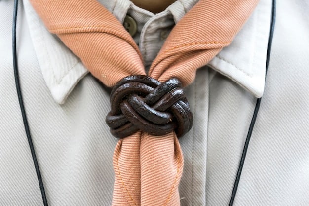 A close-up shot of hands skillfully tying a unisex scarf into a Parisian knot, showcasing the smooth fabric and detailed folds of the knot, capturing the elegance of the styling technique.