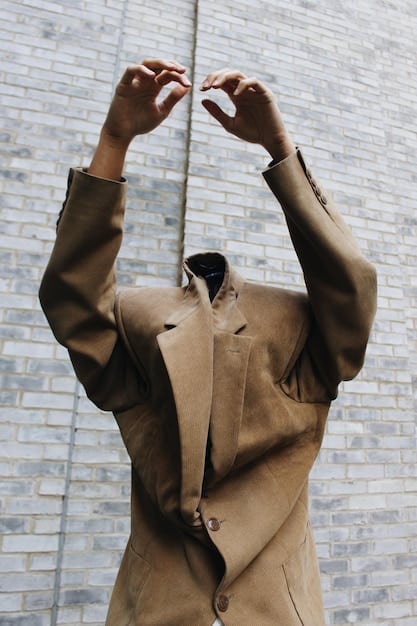 Close-up shot of an oversized blazer with deconstructed elements, such as exposed seams and asymmetrical cuts. The fabric is a mix of textures, including tweed and leather. The image highlights the innovative design and attention to detail in non-binary fashion.