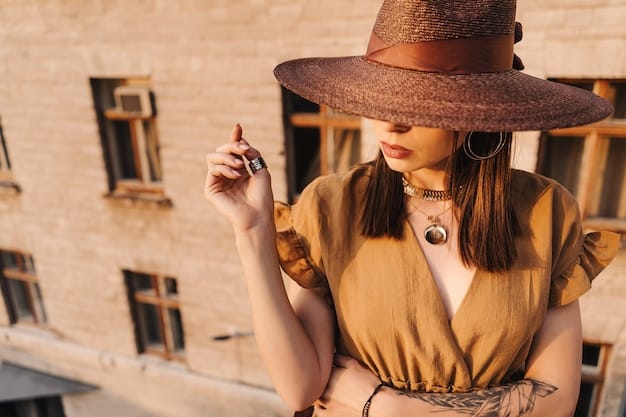 A person wearing a variety of accessories: a wide-brimmed hat, several layered necklaces, a collection of rings, and a scarf wrapped around their wrist. The accessories are a mix of metals, beads, and fabrics.