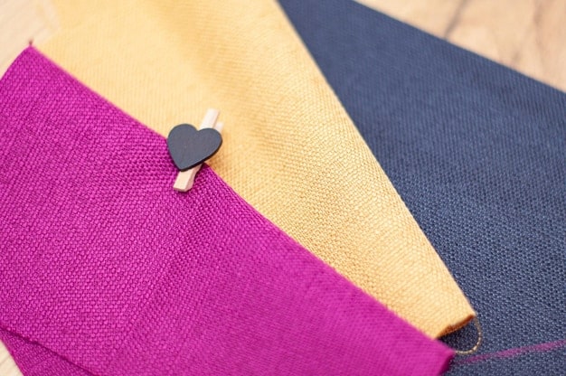 A close-up shot of different fabric textures and colors, emphasizing quality and versatility for أساسية clothing pieces: denim, cotton, wool, and a synthetic blend, arranged to highlight their individual textures.