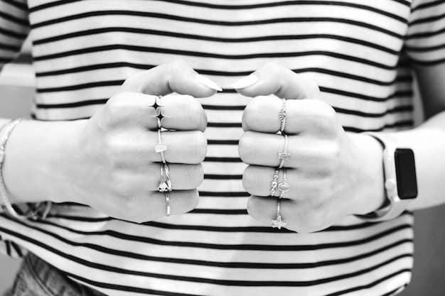 Close-up shot of hands adorned with multiple rings of varying sizes and styles, showcasing a blend of metals and unique designs, set against a backdrop of neutral-toned clothing. The image emphasizes the artistry and detail of using rings as statement pieces in non-binary fashion.