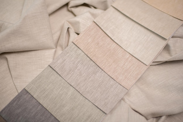 Close-up shot of various fabric swatches (cotton, linen, modal) showcasing different textures and weights. The lighting highlights the natural feel of the fabrics.