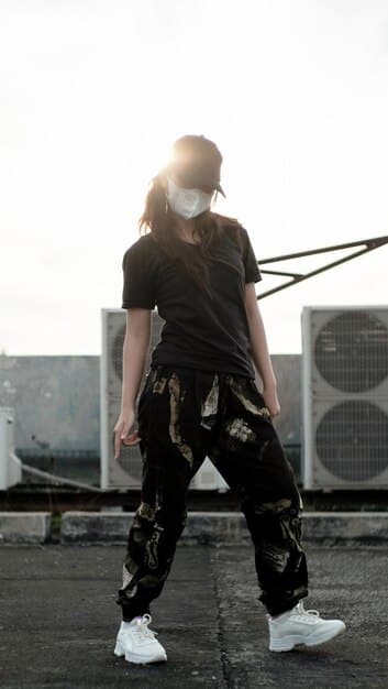 A person wearing high-waisted wide-leg cargo pants with a cropped hoodie, chunky sneakers, and a baseball cap. The look is edgy and urban, with a focus on oversized silhouettes.