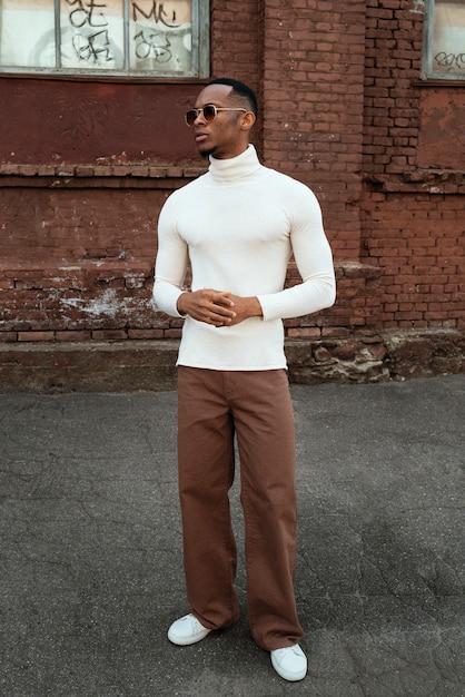 A person wearing a well-tailored suit with a relaxed fit, styled with sneakers and minimal jewelry. The suit is a neutral color, and the overall look is effortlessly chic and androgynous.