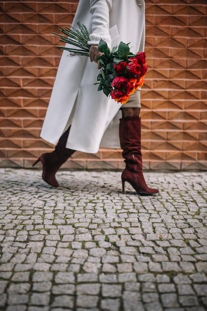 A person wearing an oversized blazer over a silky slip dress, paired with chunky boots. The contrast between the structured blazer and the delicate dress creates a balanced androgynous look.