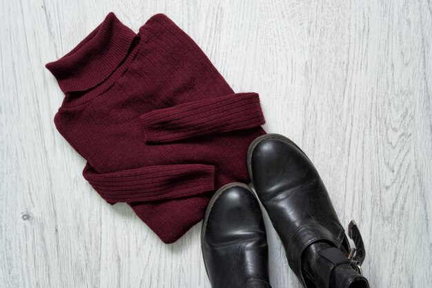 A close-up shot of various androgynous clothing items laid out on a flat surface. These include corduroy pants, oversized blazers, graphic T-shirts, oxford shirts, and combat boots arranged to showcase the variety of textures and styles.