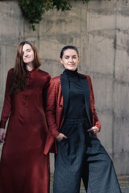 Two people on a date night, showcasing modern minimalist androgynous outfits. One is wearing a black turtleneck with tailored grey trousers, while the other is in a white button-down shirt with black wide-leg pants.