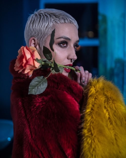 A close-up shot of someone wearing a vibrant androgynous outfit, featuring a mix of bold colors and patterns. The focus is on the clothing and accessories, highlighting the creative use of color in androgynous fashion.