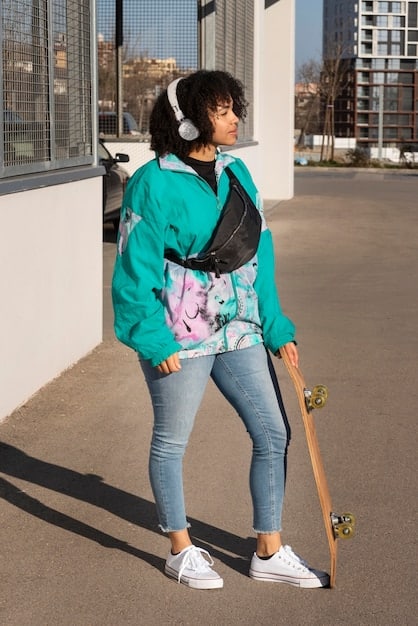 A person wearing a light grey trench coat over a white t-shirt and dark wash jeans, accessorized with a simple silver necklace and white sneakers, showcasing a casual yet put-together look.