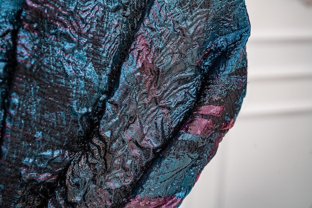 A close-up shot of layered androgynous clothing. Focus on the textures and colors of the garments, which include a wool coat, a flannel shirt, and a cotton t-shirt. The image highlights the contrast and harmony between the different layers.