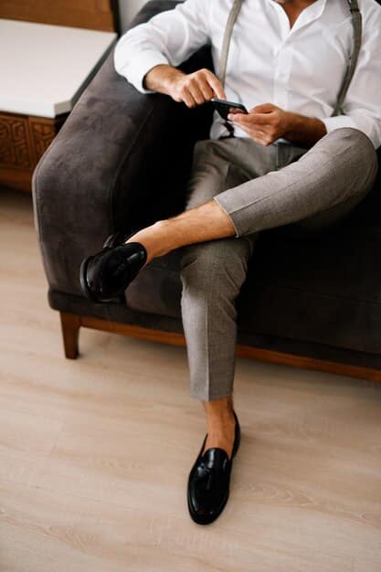 A close-up shot of a person's feet wearing elegantly designed, gender-neutral leather loafers paired with perfectly tailored, neutral-toned trousers, emphasizing sophisticated minimalism.