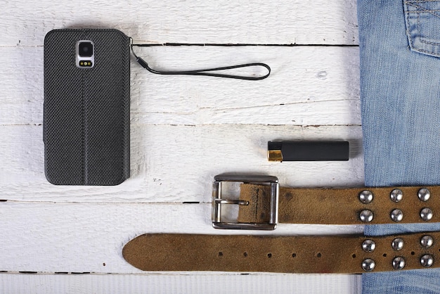 A flat lay display of various unisex accessories, including a sleek leather belt, a stylish beanie, a minimalistic silver necklace, and unique rings, all arranged harmoniously on a neutral background, highlighting their potential for cohesive styling.