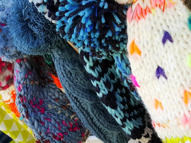 A close-up shot of various clothing items layered together, showcasing different textures and colors. The items include a denim jacket, a flannel shirt, a graphic tee, and a bomber jacket. The background is a soft, diffused light, highlighting the details of the fabrics.