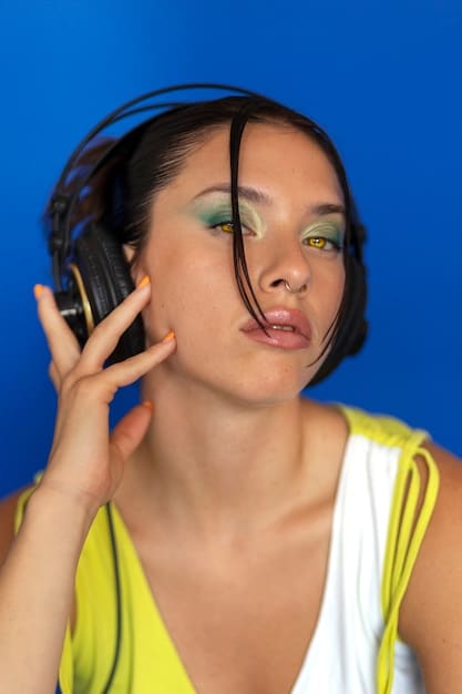 A non-binary person with bold makeup, featuring graphic liner in a neon color and a glossy lip. The setting is a vibrant, urban backdrop.