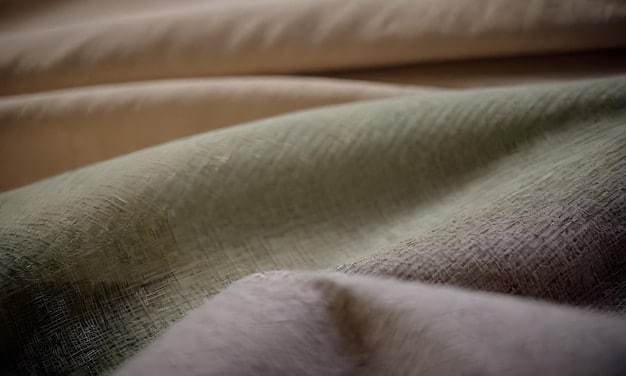 Close-up of several fabric swatches in neutral tones like grey, beige, and olive green, with textures ranging from smooth wool to slightly rough linen.