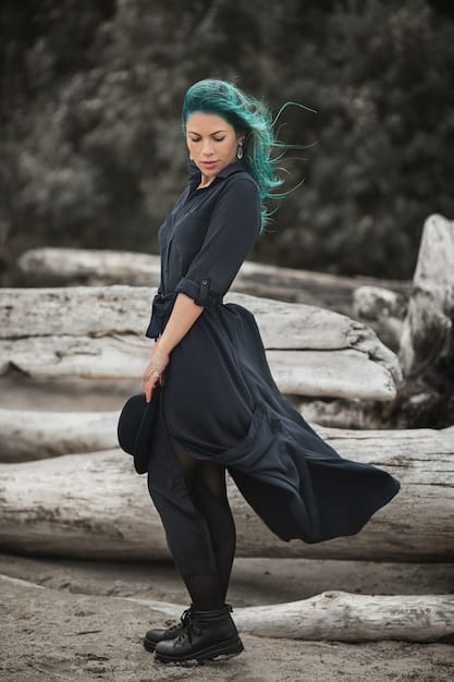 A non-binary person with long hair, wearing a long, flowing, non-gender-specific outfit with bold accessories, demonstrating androgynous fashion.