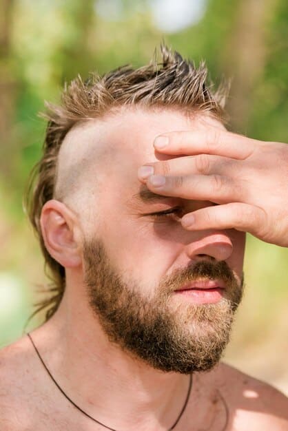 A close-up of a man's hand using a blotting paper to gently dab his forehead, with a subtle, non-shiny finish indicative of well-maintained foundation, in an outdoor setting.