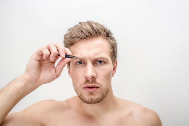 A man using the spoolie end of a brow brush to comb his eyebrows upwards and into place, showing a natural, well-groomed brow.