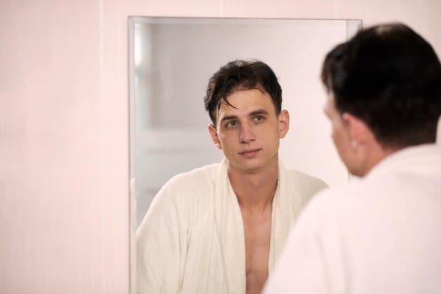 A man in his late 20s or early 30s confidently looking in a mirror, his skin appearing clear and even-toned, subtly enhanced, not overly made up.