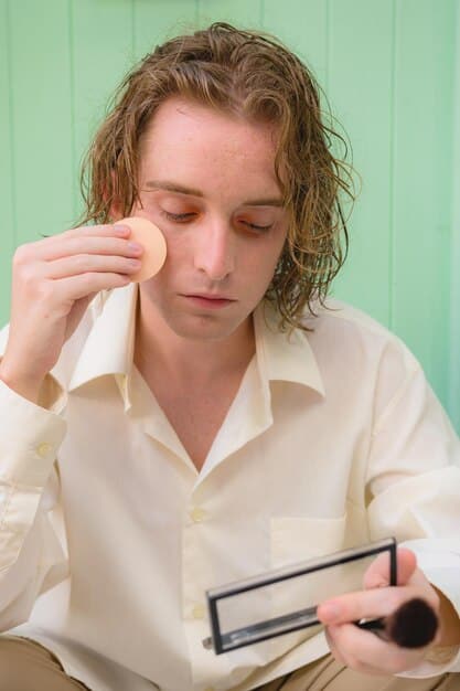 A man subtly applying a lightweight, natural-looking foundation to his face using his fingertips, showcasing a practical and discreet application method.