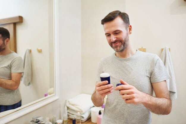A man in his 30s carefully applies a small drop of serum to his forehead, focusing on even distribution, with a clean and minimalistic bathroom background.