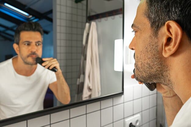 A man intently examining his skin in a bathroom mirror after using a facial cleansing brush, focusing on the texture and clarity of his complexion.