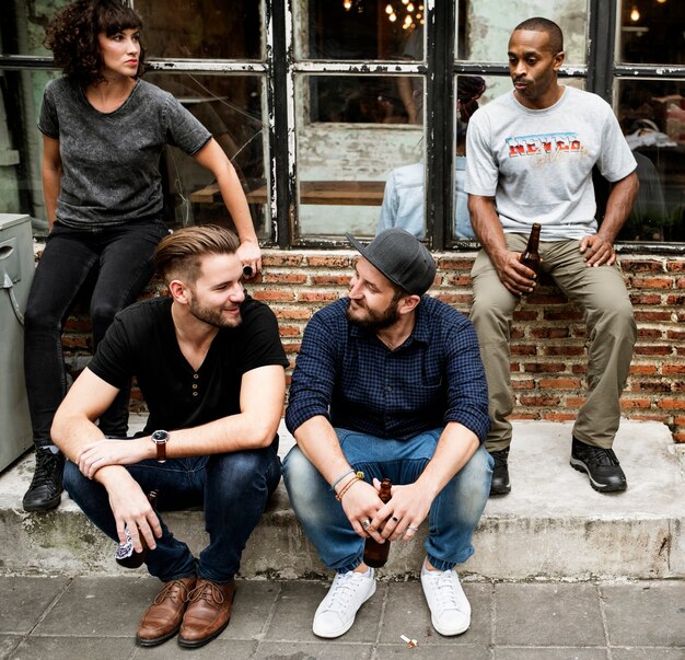 A group of creative and diverse young men in an urban setting, some wearing subtle face makeup and others with bolder elements like nail polish or eye glitter, showcasing a broader embrace of male cosmetic expression beyond just eyeliner, with a vibrant, inclusive atmosphere.