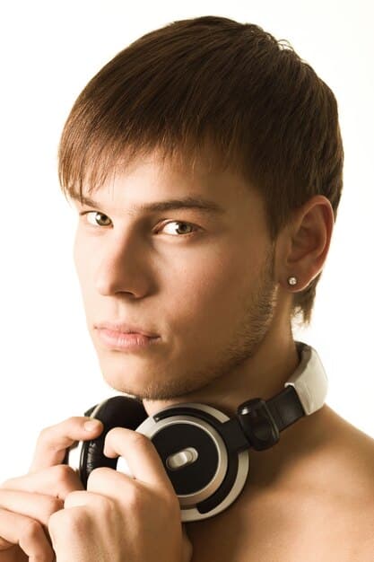 A male model with a subtle, radiant makeup look, showcasing a healthy glow on his cheekbones and a soft eye highlight, implying sophisticated and modern male aesthetics.