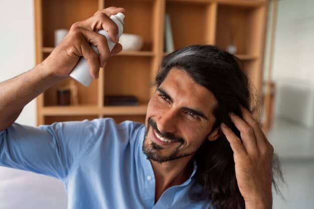 A man in his 30s applying a clear, foamy substance to his scalp with his fingertips, looking focused. The bathroom mirror reflects him, showing the product bottle on the counter. The image conveys ease of use and personal care.