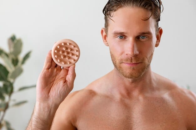 A close-up shot of a man applying a styling clay to his hair, showing the product's texture and his hands working through his hair, emphasizing natural movement and hold.