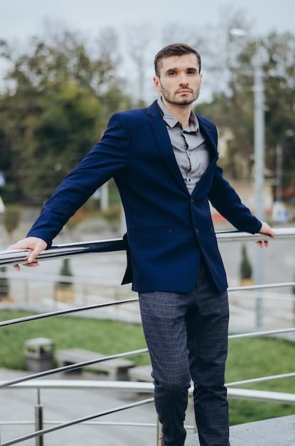 A man dressed in a stylish smart casual outfit. He's wearing a navy blazer, a white button-down shirt, dark wash jeans, and brown leather loafers. The setting is a relaxed urban backdrop. The image illustrates how to combine formal and casual elements effectively, as emphasized in Decoding Dress Codes: A Man's Guide to Navigating Any Occasion in 2025.