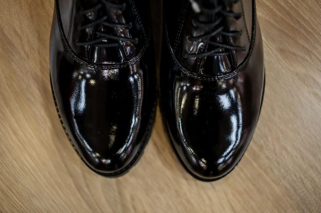 A close-up shot of a pair of meticulously crafted black leather Oxford shoes. The shoes are highly polished, reflecting light and showcasing the intricate stitching and design. The background is blurred, emphasizing the elegance and sophistication of the footwear.