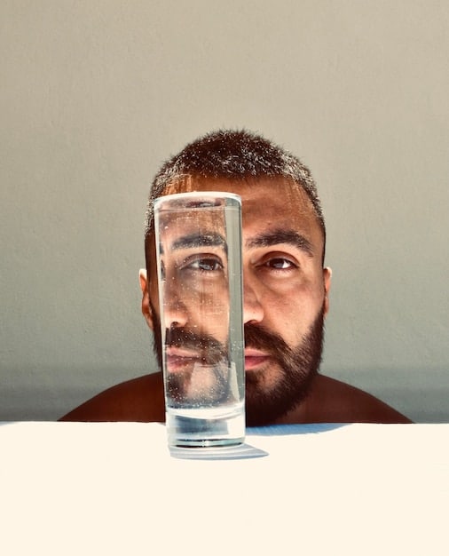 A man drinking a glass of water, with a focus on the glass and the man's hand holding it. The background should be a blurred, modern kitchen to give context. Symbolizes the importance of internal hydration as part of Combat Dry Winter Skin: The Ultimate Hydration Routine for Men in 2025.