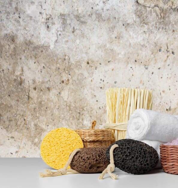 A variety of men's exfoliating products neatly arranged on a bathroom shelf: a scrub, a chemical exfoliant bottle, and an exfoliating brush. The lighting is bright and clean, emphasizing the product textures and packaging.
