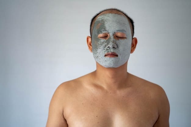 A man with a towel around his neck is applying a clay mask to his face with a brush. The background is a well-lit bathroom with modern fixtures. Focus on the clay mask application, the detail makes it clear how much he cares about his look. The ultimate guide to men's face masks: deep clean and hydrate shown in top.