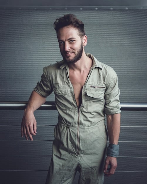 A man with perfectly maintained stubble, showcasing a rugged yet refined appearance. He is wearing a casual outfit, and the background is a well-lit outdoor setting, emphasizing the natural and understated style. Beyond the Beard: Exploring New Facial Hair Styles Trending Now is achieved flawlessly with this look.