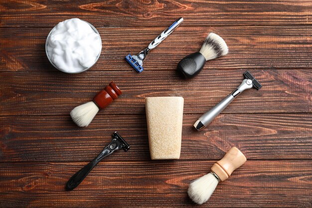 A set of classic men's grooming tools, including a straight razor, a badger hair shaving brush, a silver shaving bowl, and a block of traditional shaving soap. The items are arranged on a dark wooden surface, emphasizing their quality and craftsmanship related to The Comeback of Classic Styles: Are Traditional Grooming Techniques Making a Return?.