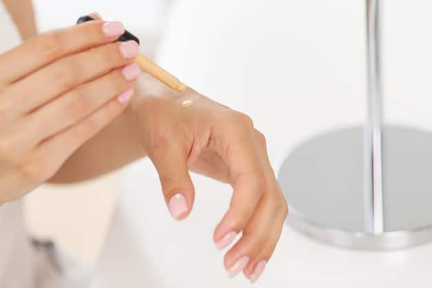 A hand applying concealer from a stick directly onto the skin. The fingers are lightly blending the product, showing how it looks and feels upon application. The skin looks slightly moist.